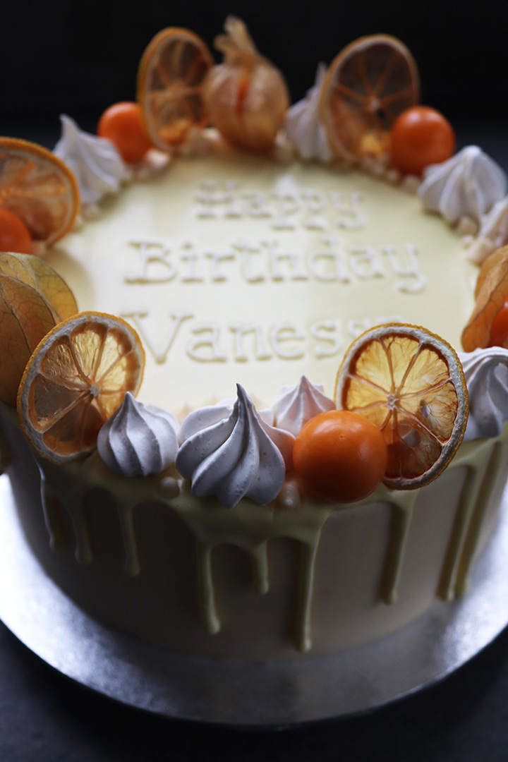 Warm notes of Madagascar vanilla combine with the sharp tang of lemon zest and juice in this luscious layer cake. Made with organic ingredients, this is also available as a dairy-free cake. Decorated here with meringue kisses, dried lemon slices and fresh physalis