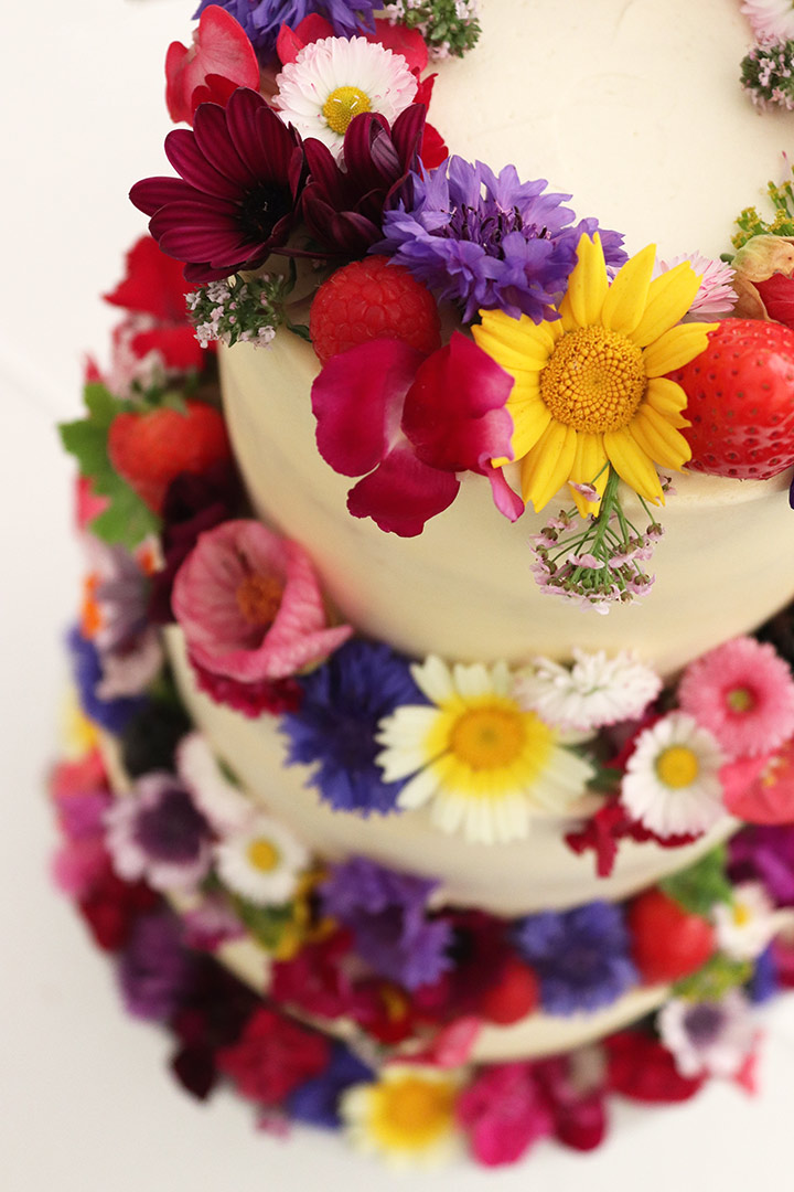 A semi-nude gluten free May wedding cake in London. Three flavours: Coconut & Lime, Layered Tunisian Orange & Almond, and Layered Chocolate & Olive Oil Cake. All ingredients glutenfree. Decorated with organic edible flowers. Price includes tasting consultation, and delivery and assembly at your London venue