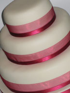 A gorgeous gluten-free, wheat-free 3 tier wedding cake. Top tier: moist ginger cake, gluten free and dairy free. Middle tier: gluten-free and dairy-free orange and almond cake. Bottom tier: glutenfree chocolate and hazelnut cake. All cakes are gluten free and wheat free, made with organic ingredients. Topped with organic marzipan and smooth ivory icing, and decorated with silk ribbons: the perfect centrepiece for your gluten-free wedding 