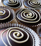 A selection of cakes made with rum etc. In the picture, delightful gluten-free mini chocolate and almond cupcakes, made with organic dark Fairtrade chocolate and ground almonds and Appleton Jamaica Rum, and topped with dark chocolate ganache and white chocolate swirls. For collection or delivery in London. Can be posted to UK addresses
