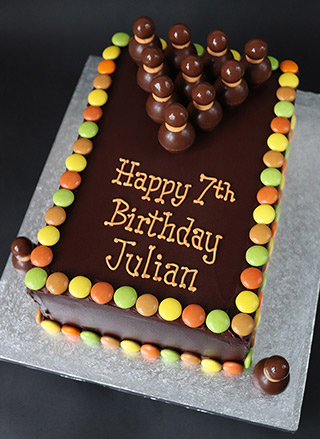 A gluten-free Chocolate Bowling Cake. Layers of glutenfree vanilla & chocolate sponge, filled with vanilla buttercream & covered with organic chocolate ganache. Decorated with gluten free chocolate balls & beans