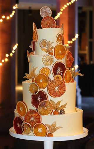 A four-tier winter wedding cake. Two tiers of gluten-free lemon cake, and two of orange. Filled and frosted with sweet & sharp organic buttercream, and decorated with dried orange, grapefruit & lemon slices. All ingredients gluten free. Price includes tasting consultation, and delivery & assembly at your London venue