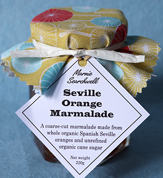Seville Orange Marmalade: Coarse cut, made with organic Spanish Sevilles (hand cut), unrefined cane sugar and blackstrap molasses - dark and intense. Once tasted, nothing else comes close: this is the perfect gift for the marmalade connoisseur. Finished with pretty fabric topper tied with paper ribbon