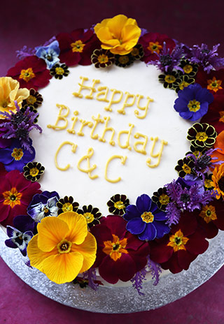 Gluten free birthday cake: 2 layers of dairyfree Orange & Almond cake, filled with orange Swiss meringue buttercream and decorated with organic edible flowers. All ingredients gluten-free. Delivery in London and the southeast