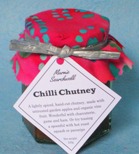 Chilli Chutney: A classic hand-cut chutney made with untreated garden apples and organic vine fruit, with a little chilli kick that won't blow your head off! Wonderful with ham and game, or tossed with hot roast parsnip or pumpkin. Finished with a fabulous fabric topper tied with silver paper ribbon 