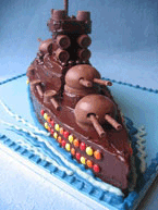 Chocolate Battleship Cake, made with organic gluten-free chocolate sponge. Filled with chocolate buttercream and frosted with dark chocolate ganache. Decorated with glutenfree chocolate beans, sweets and biscuits. Delivered to Wimbledon